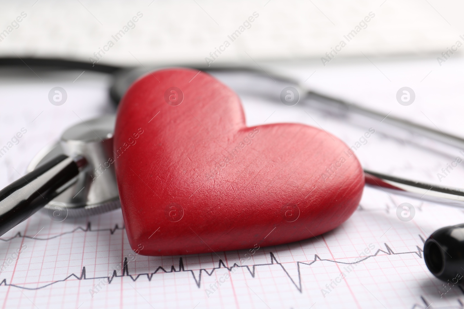 Photo of Cardiology. Stethoscope and red decorative heart on paper with cardiogram, closeup