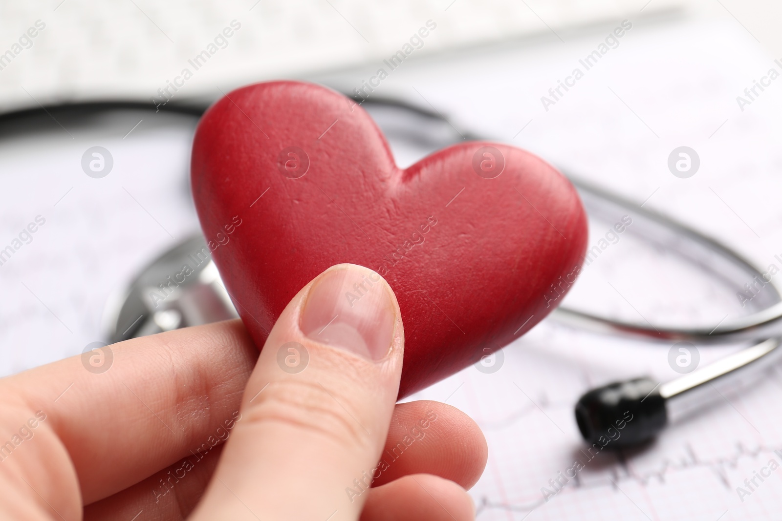 Photo of Cardiology. Woman with red decorative heart on blurred background, closeup