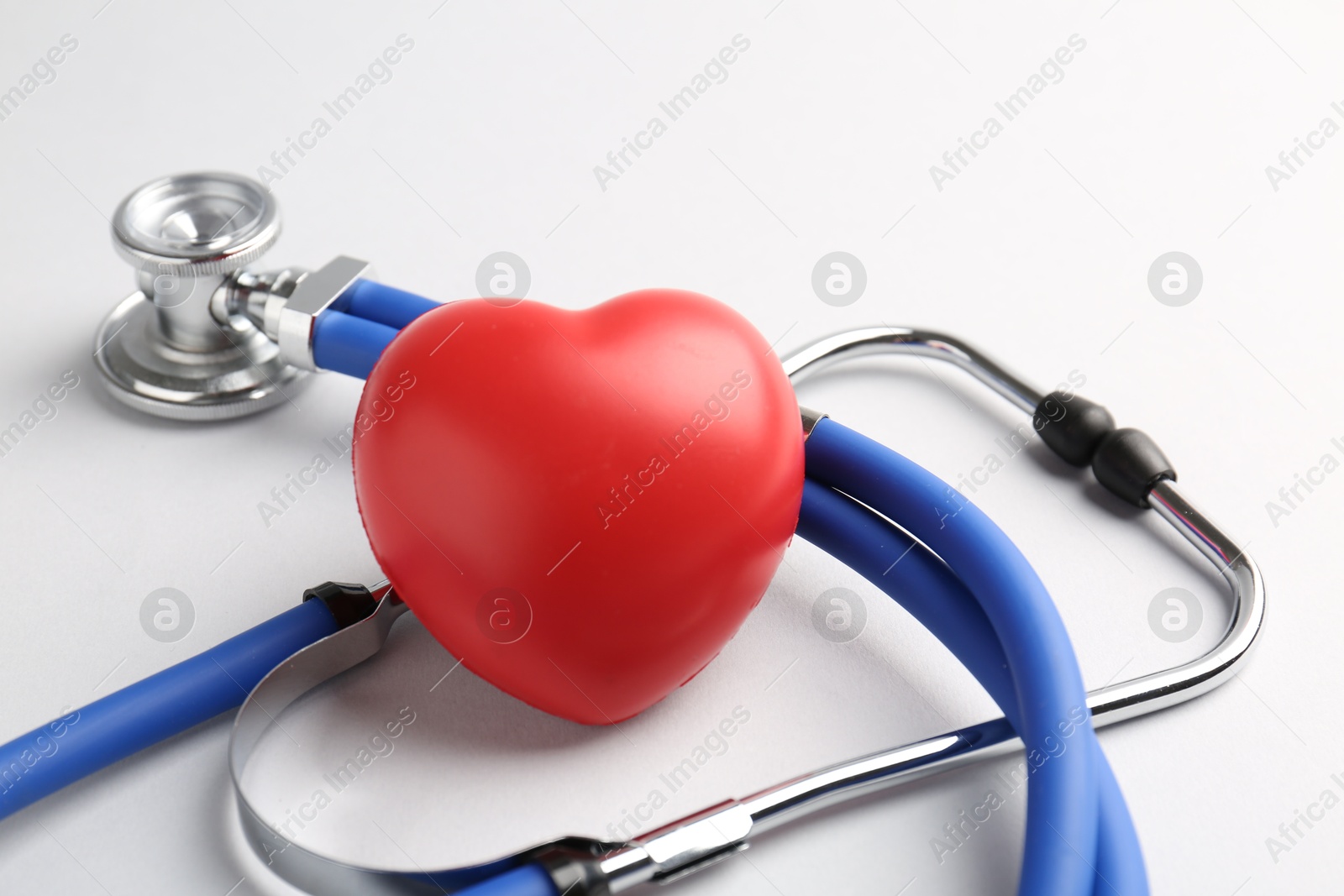 Photo of Cardiology. Stethoscope and red decorative heart on white background, closeup