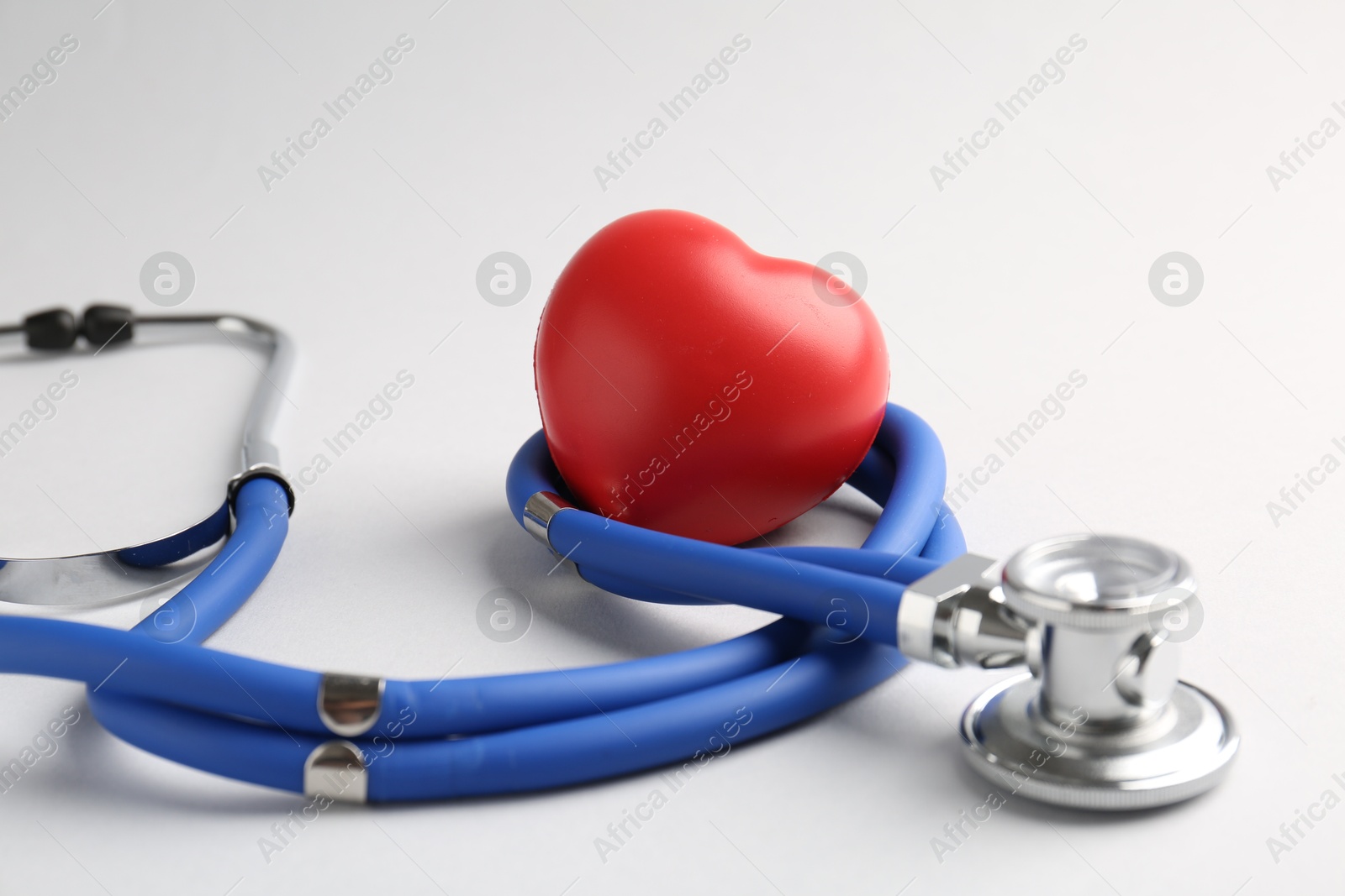 Photo of Cardiology. Stethoscope and red decorative heart on white background, closeup