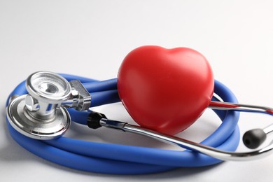 Photo of Cardiology. Stethoscope and red decorative heart on white background, closeup