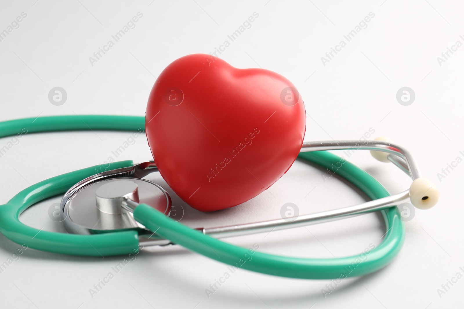 Photo of Cardiology. Stethoscope and red decorative heart on white background, closeup