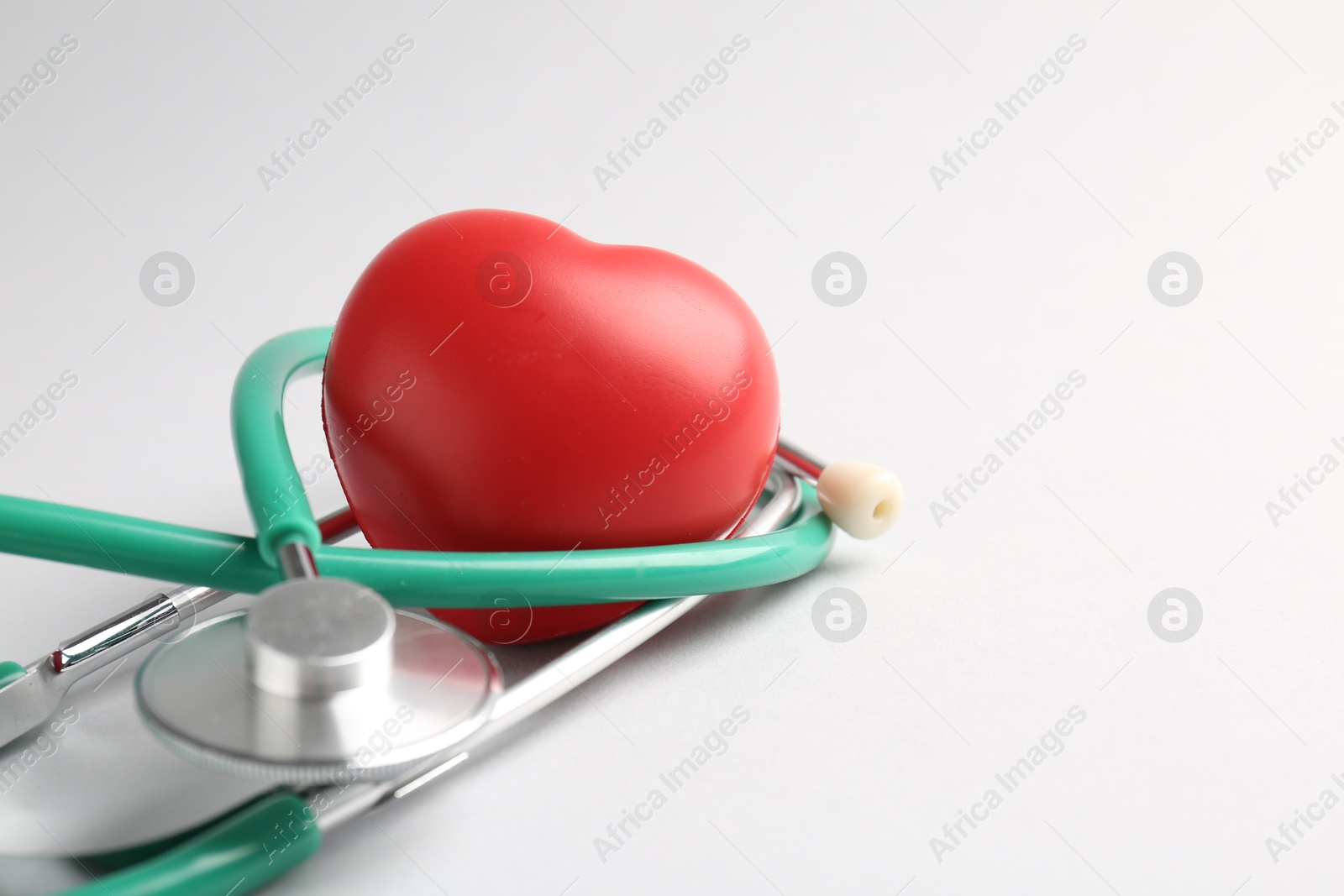 Photo of Cardiology. Stethoscope and red decorative heart on white background, closeup. Space for text