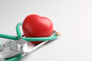 Photo of Cardiology. Stethoscope and red decorative heart on white background, closeup. Space for text