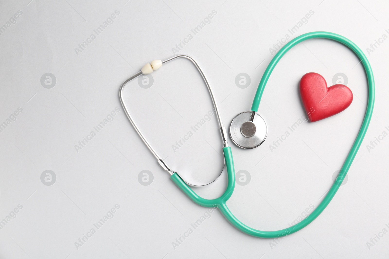 Photo of Cardiology. Stethoscope and red decorative heart on white background, flat lay. Space for text