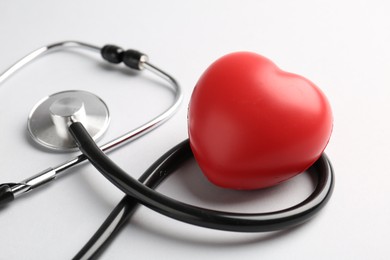 Photo of Cardiology. Stethoscope and red decorative heart on white background, closeup