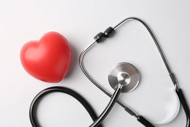 Photo of Cardiology. Stethoscope and red decorative heart on white background, flat lay