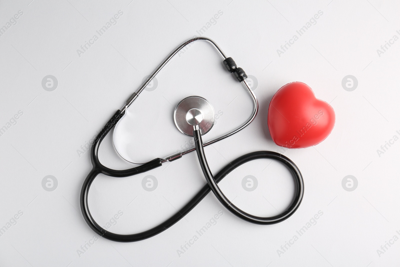 Photo of Cardiology. Stethoscope and red decorative heart on white background, flat lay