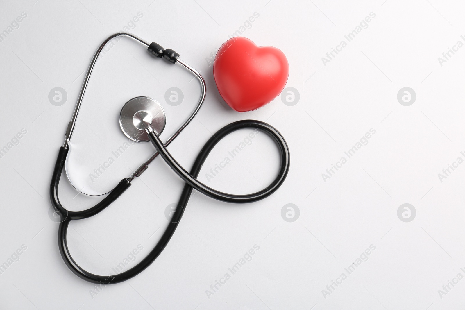 Photo of Cardiology. Stethoscope and red decorative heart on white background, flat lay. Space for text