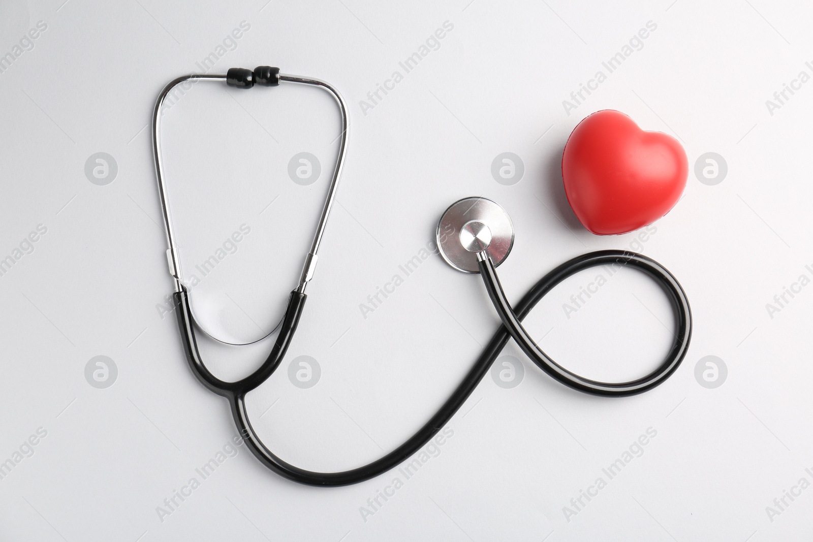 Photo of Cardiology. Stethoscope and red decorative heart on white background, flat lay