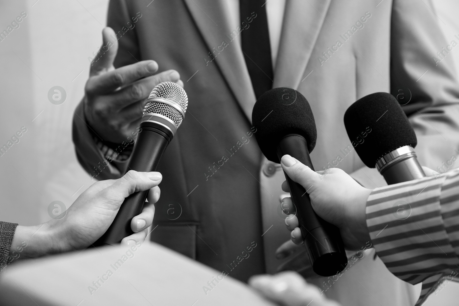 Image of Journalists interviewing businessman indoors, closeup. Toned in black-and-white