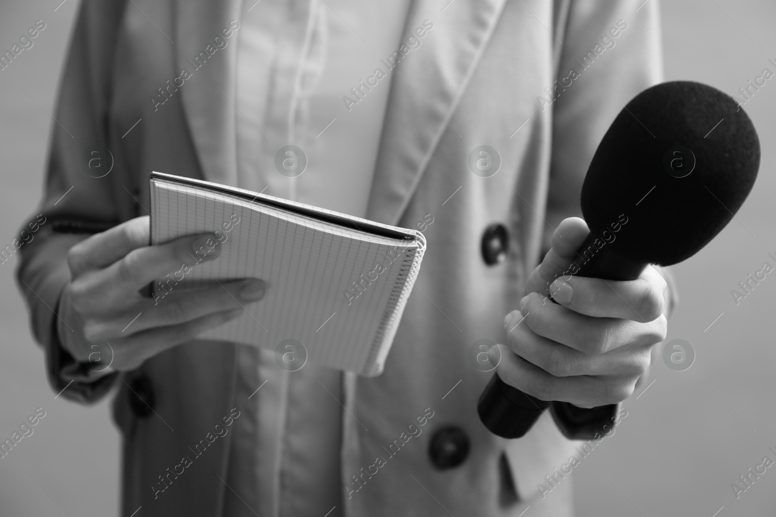 Image of Journalist with microphone and notebook, closeup. Toned in black-and-white