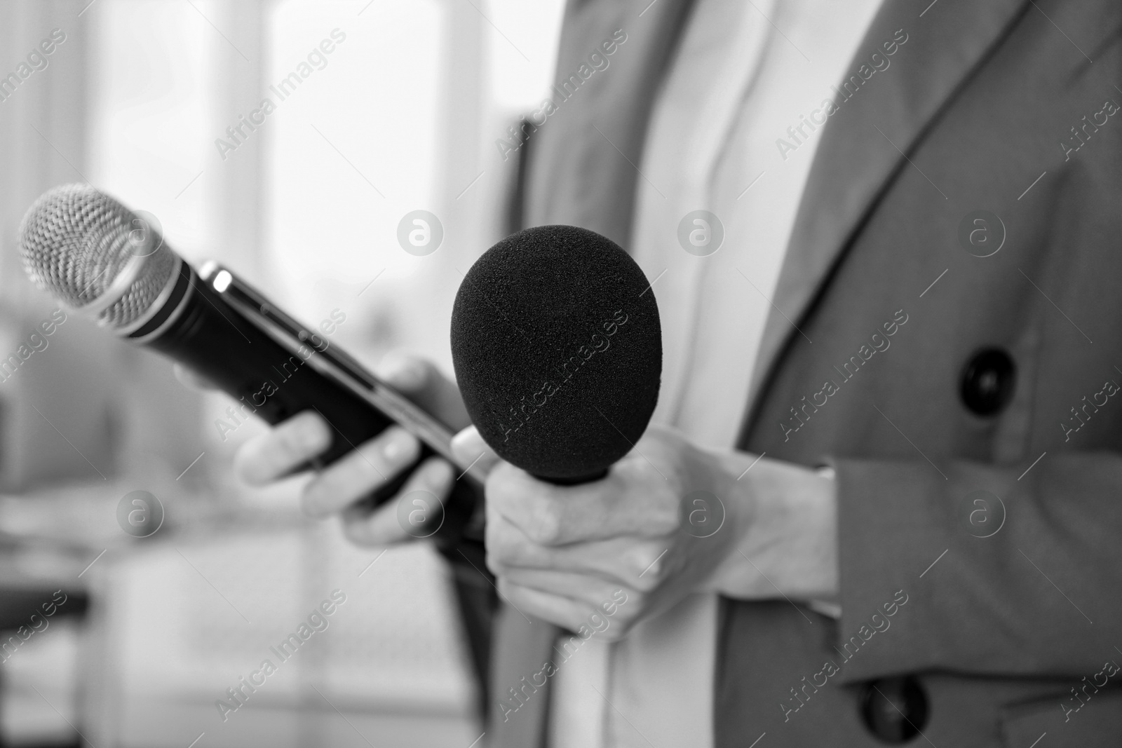 Image of Journalist with microphones and mobile phone, closeup. Toned in black-and-white