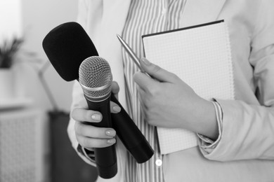 Image of Journalist with microphones and notebook, closeup. Toned in black-and-white