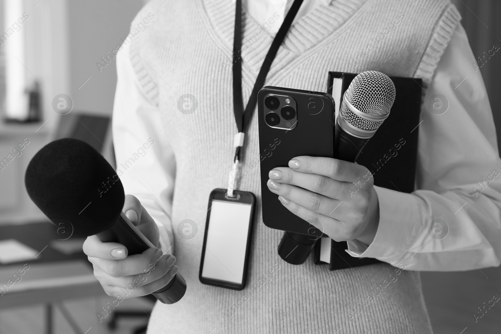 Image of Journalist with microphones, mobile phone and notebook, closeup. Toned in black-and-white