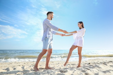 Photo of Happy young couple holding hands on beach