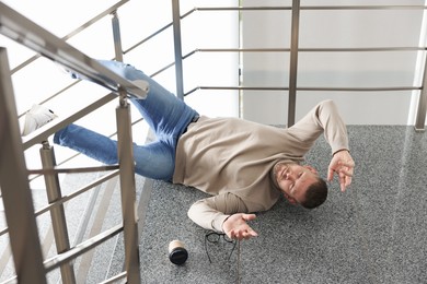 Photo of Injured man on stairs in building after fall. Dangerous accident