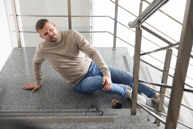 Photo of Injured man on stairs in building after fall. Dangerous accident