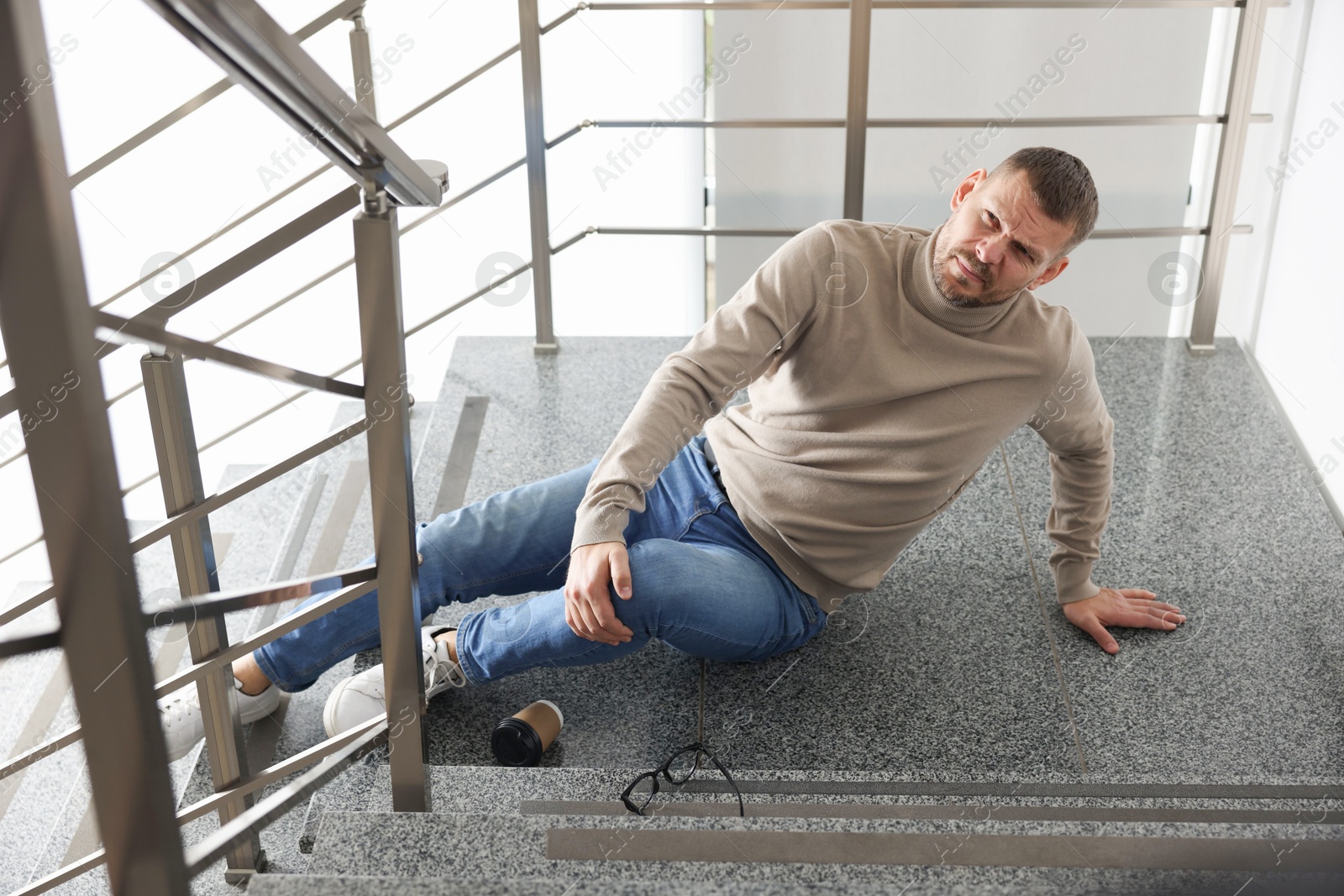 Photo of Injured man on stairs in building after fall. Dangerous accident