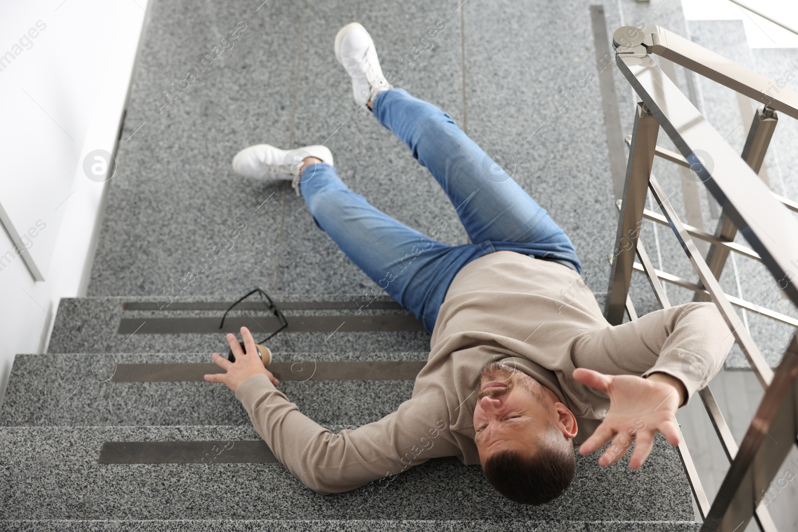 Photo of Injured man on stairs in building after fall, above view. Dangerous accident