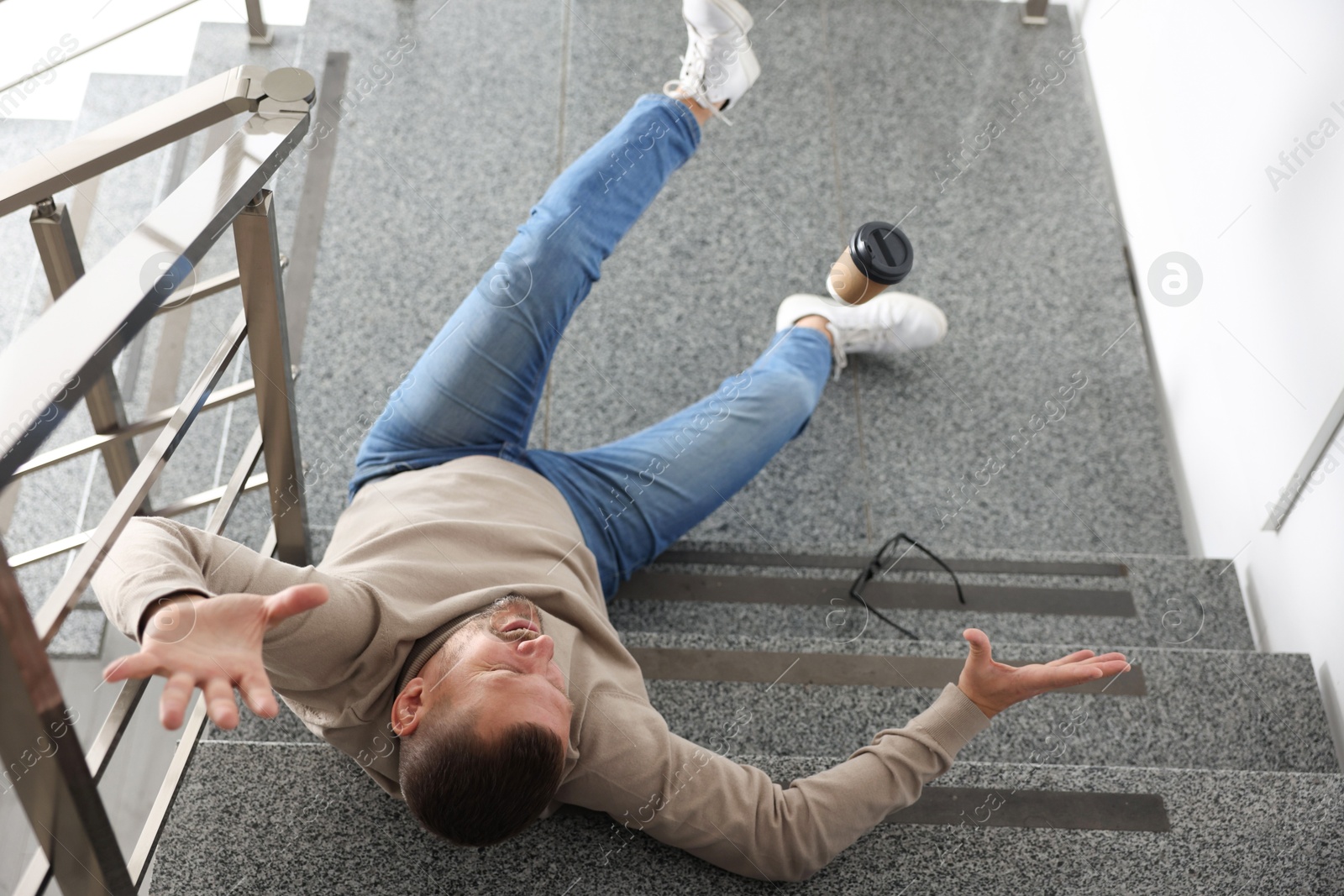 Photo of Injured man on stairs in building after fall, above view. Dangerous accident