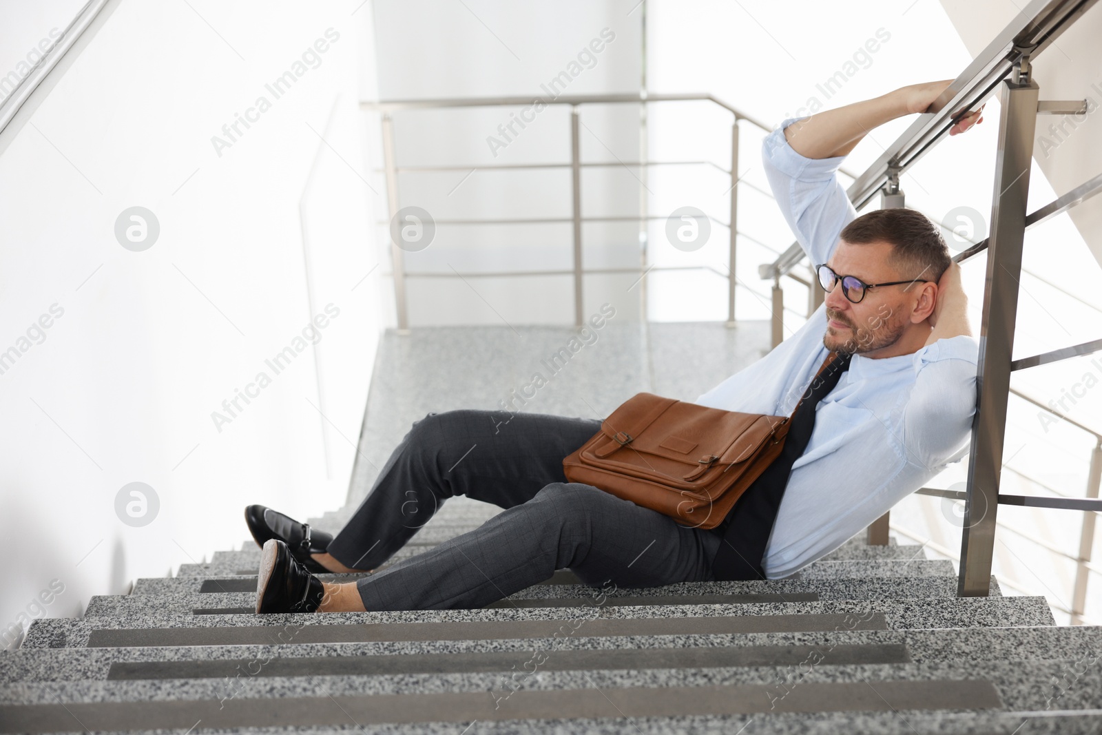 Photo of Man with injured head on stairs in building after fall. Dangerous accident