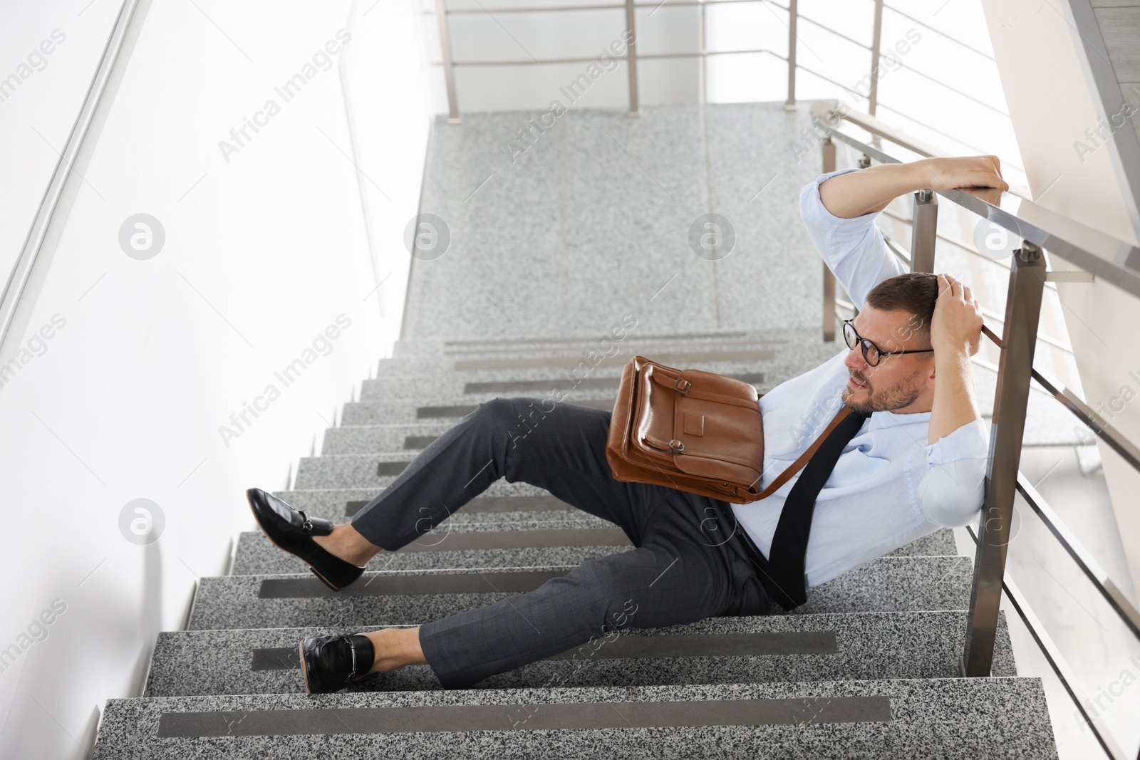 Photo of Man with injured head on stairs in building after fall. Dangerous accident