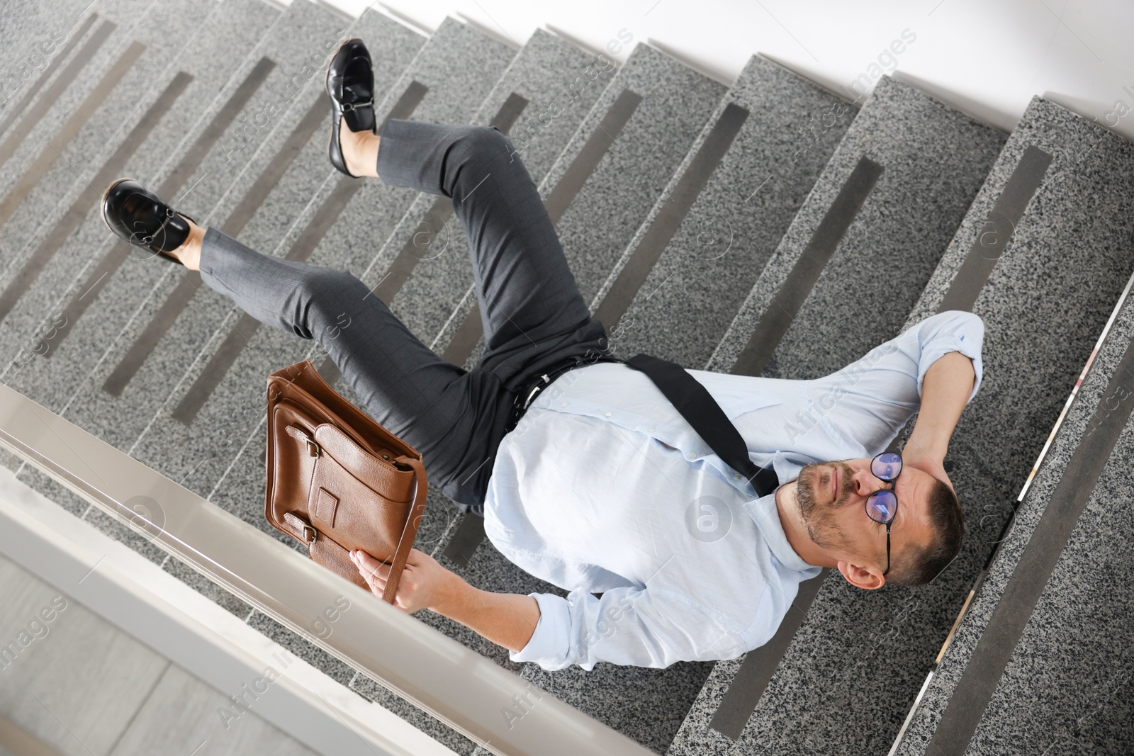 Photo of Man with injured head on stairs in building after fall, above view. Dangerous accident