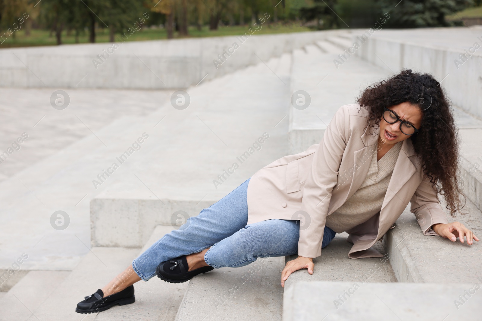 Photo of Injured woman on stairs outdoors after fall. Dangerous accident