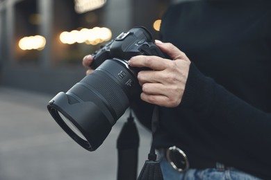 Photo of Professional photographer with digital camera outdoors, closeup