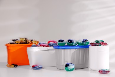 Photo of Containers with different laundry detergent capsules on white background