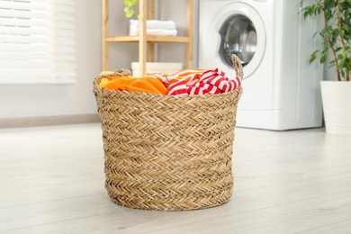 Photo of Wicker basket full of laundry in bathroom