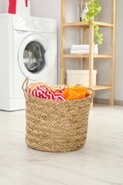 Photo of Wicker basket full of laundry in bathroom