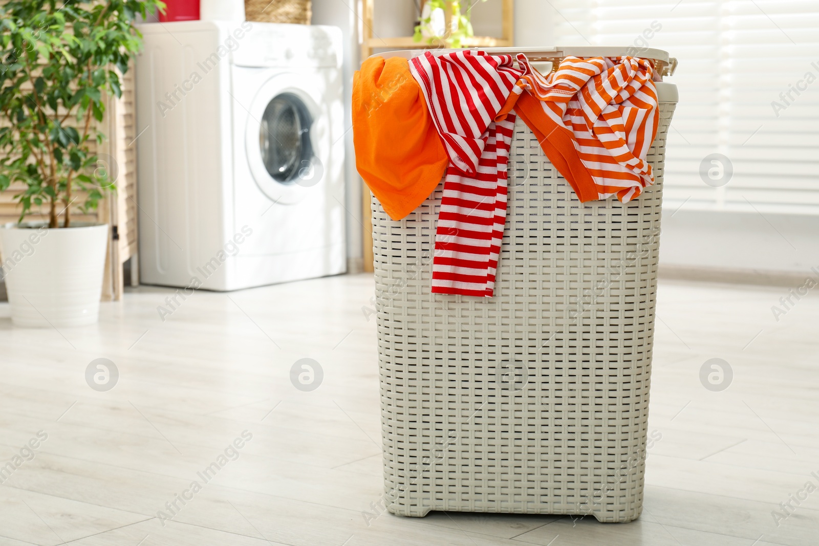 Photo of Wicker basket full of laundry in bathroom