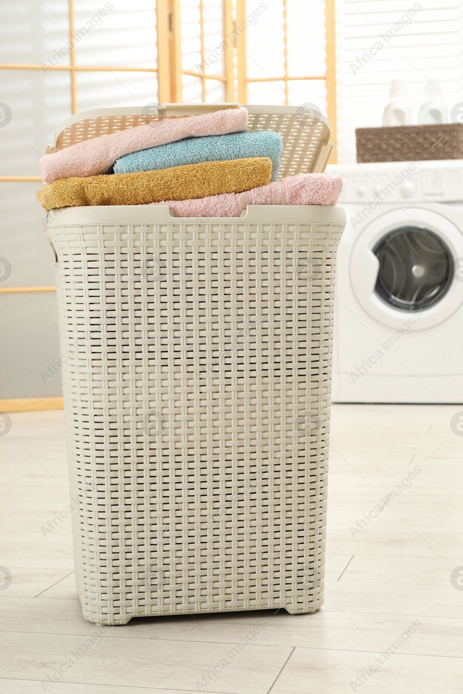 Photo of Wicker basket full of laundry in bathroom