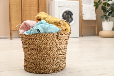 Photo of Wicker basket full of laundry in bathroom