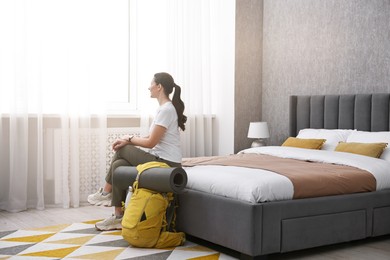 Photo of Traveller with backpack sitting on bed in hotel room