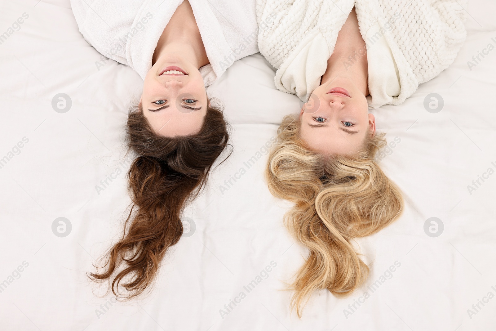 Photo of Spa day. Happy women lying on bed, above view