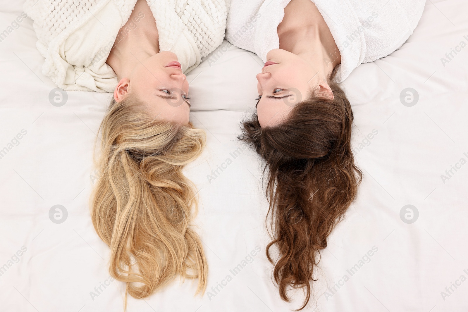 Photo of Spa day. Happy women lying on bed, above view