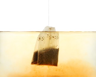 Photo of Putting tea bag into glass cup on white background, closeup