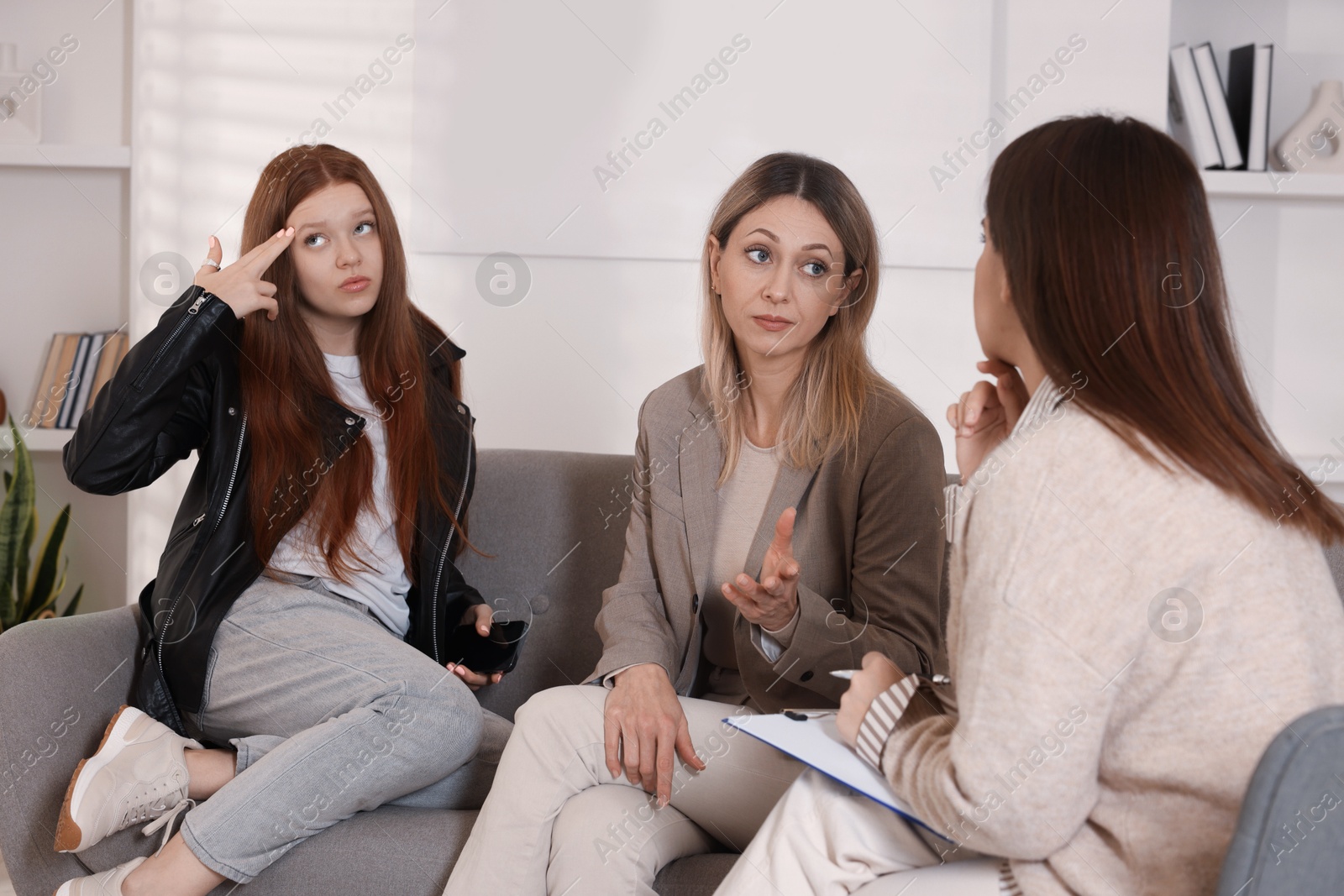 Photo of Difficult teenager. Mother and daughter having consultation with psychologist in office