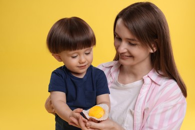 Photo of Mother and baby eating tasty mochi on yellow background