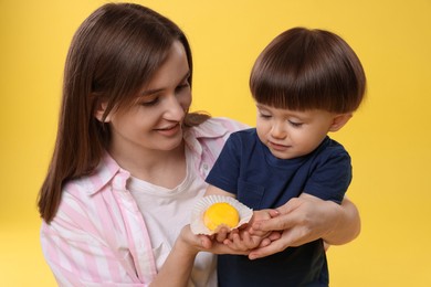 Photo of Mother and baby eating tasty mochi on yellow background