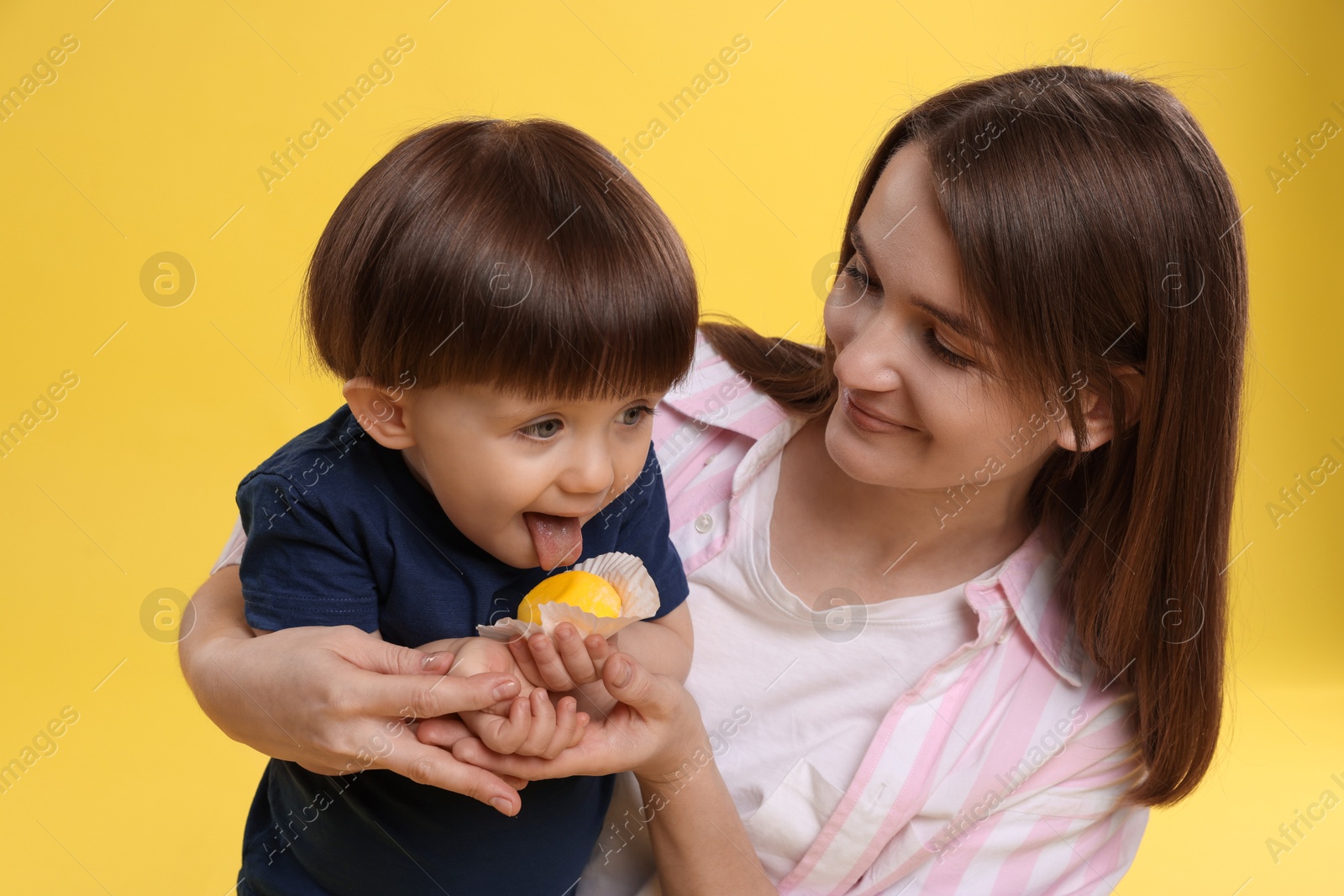 Photo of Mother and baby eating tasty mochi on yellow background