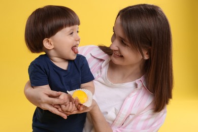 Photo of Mother and baby eating tasty mochi on yellow background