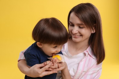 Photo of Mother and baby eating tasty mochi on yellow background