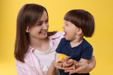 Photo of Mother and baby eating tasty mochi on yellow background