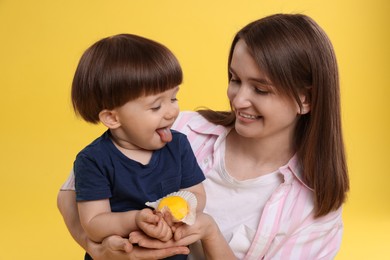 Photo of Mother and baby eating tasty mochi on yellow background