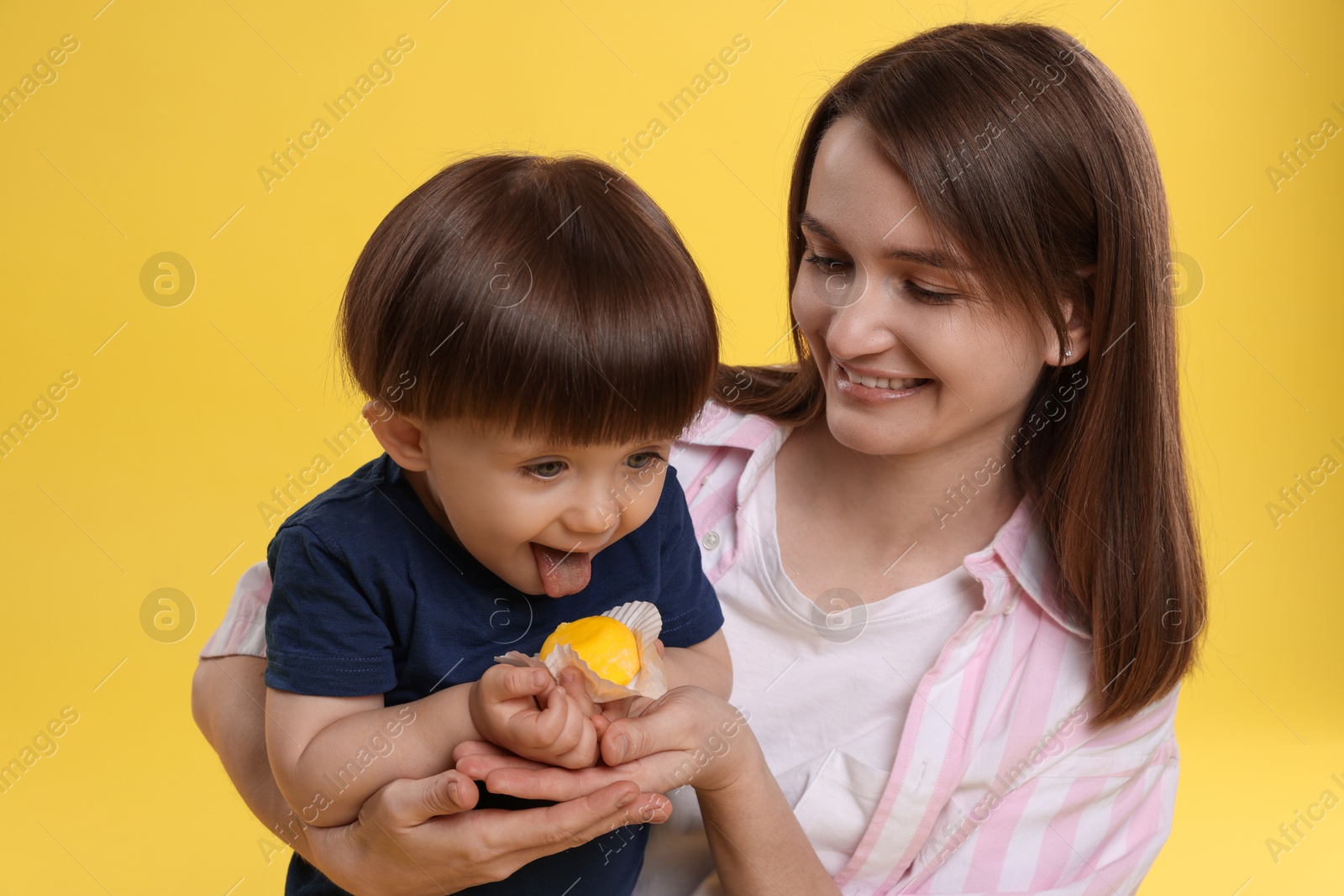 Photo of Mother and baby eating tasty mochi on yellow background