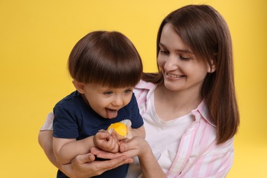 Photo of Mother and baby eating tasty mochi on yellow background